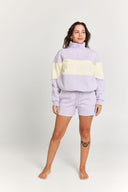 Person wearing a light purple and yellow striped quarter zip jumper with matching shorts on a white background