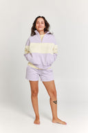Woman wearing a light purple and yellow quarter zip jumper with matching shorts on a white background