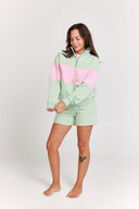 Woman wearing a light green and pink color-blocked outfit on a white background