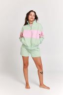 Person wearing a green and pink quarter zip jumper set on a white background